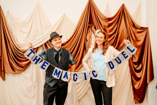 Erica and Nate holding up a "Magic Duel" banner