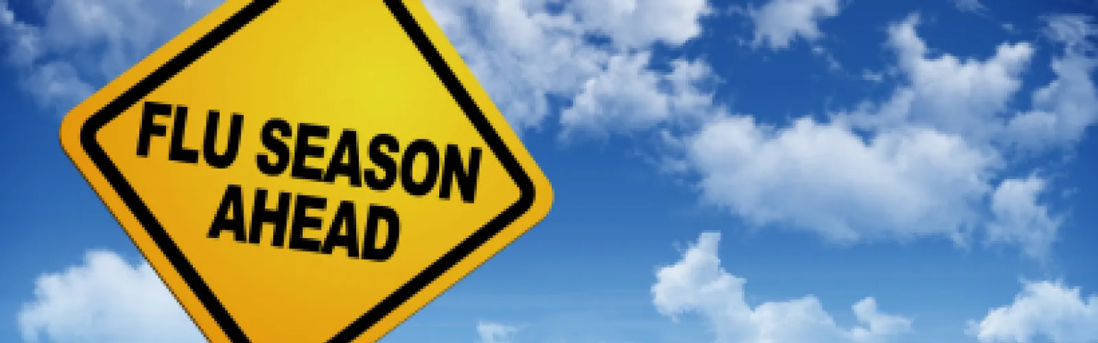 "Flu Season Ahead" on yellow road sign with blue sky and clouds