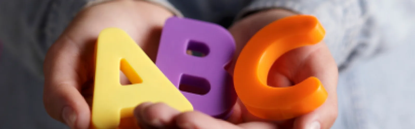 child hands holding an A, B, and C colored magnet
